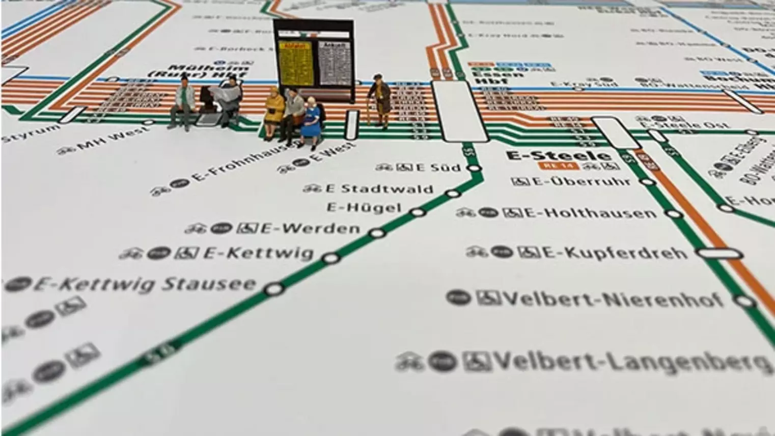 Modellfiguren sitzen auf dem VRR-Schienenschnellverkehrsplan 