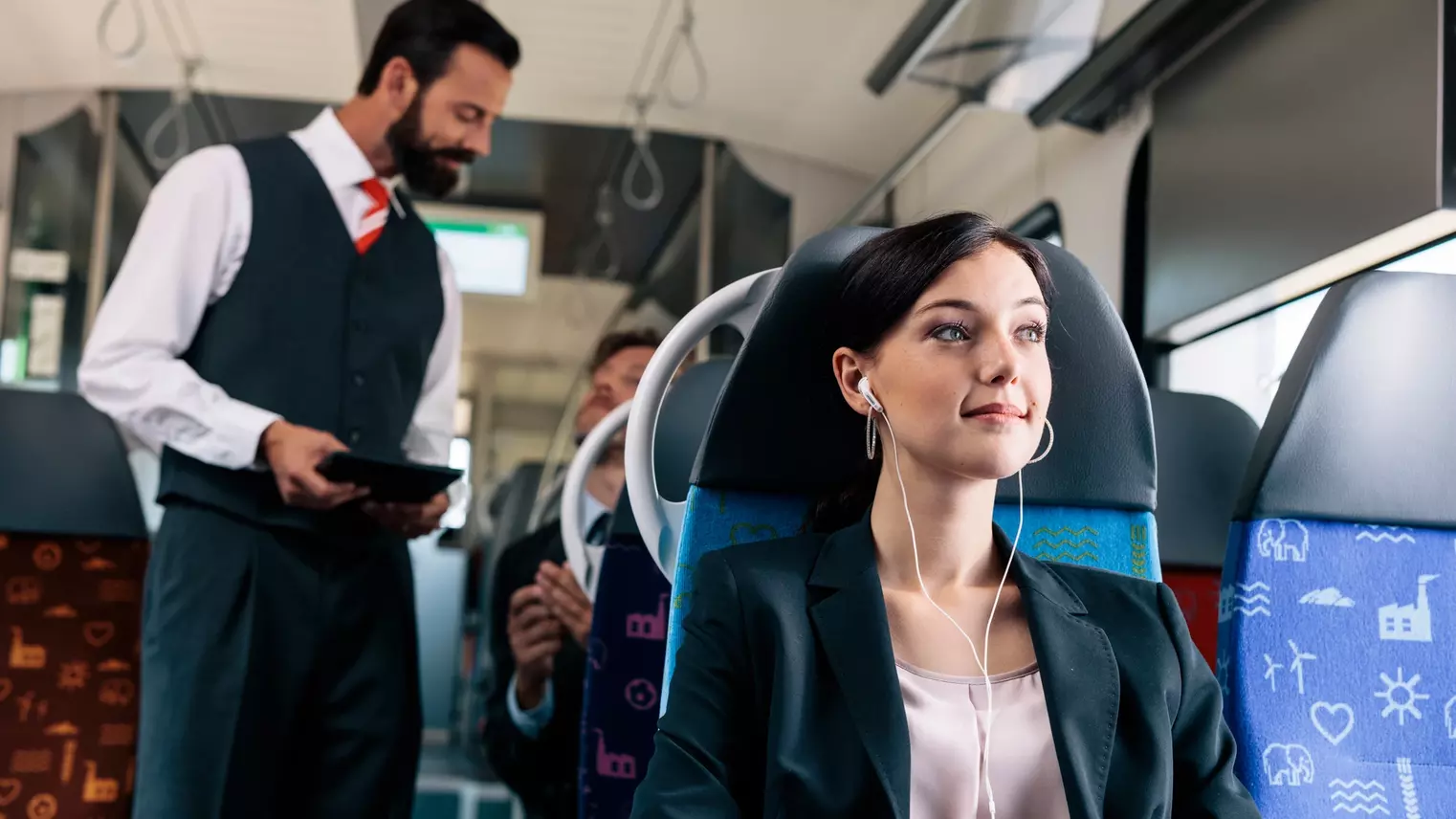 Eine Frau hört Musik in der S-Bahn, hinter ihr steht ein Kontrolleur