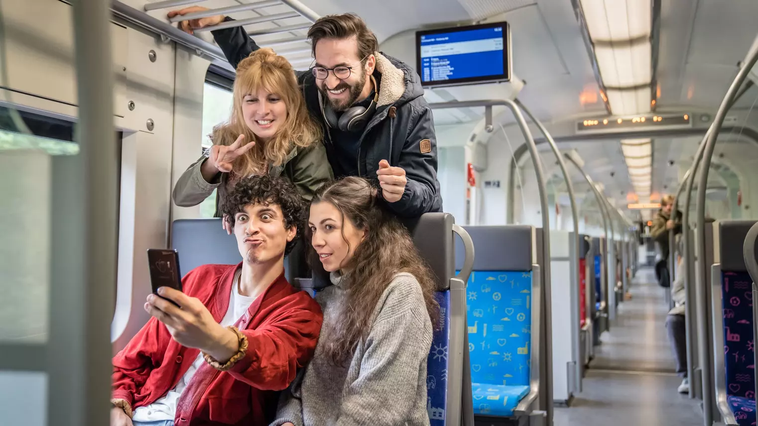 Vier Freunde nehmen ein Selfie auf den Sitzplätzen der S-Bahn auf